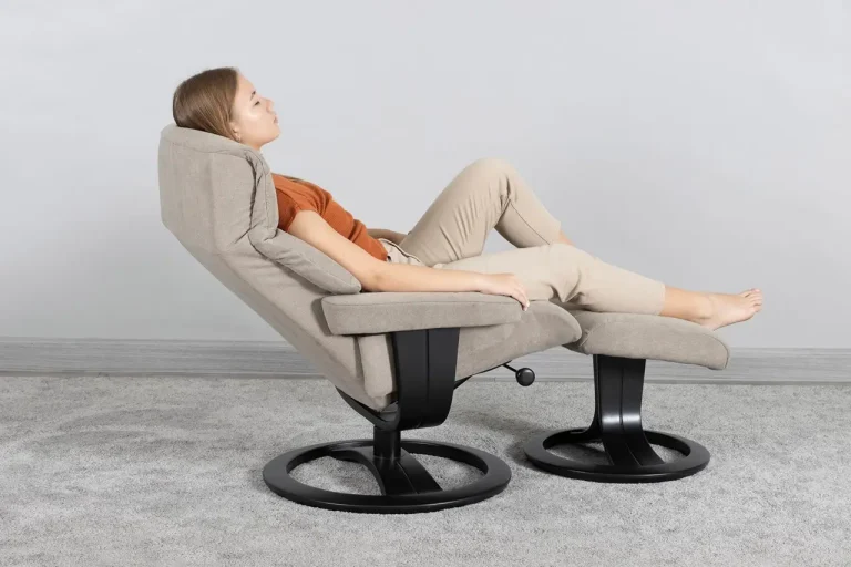 Woman relaxing on an H2 nordic style beige fabric swivel recliner with matching ottoman on black metal base