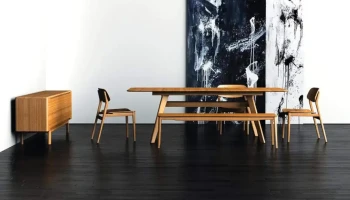 DS4 - A mid-century modern dining set with a smooth bamboo honey-toned wooden table and chairs on a dark hardwood floor