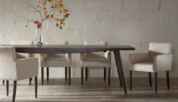 DS8 - Espresso-finished table paired with textured cream upholstered chairs against a soft white brick wall