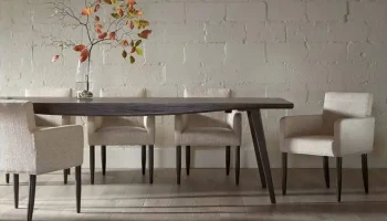 DS8 - Espresso-finished table paired with textured cream upholstered chairs against a soft white brick wall