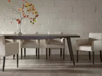 DS8 - Espresso-finished table paired with textured cream upholstered chairs against a soft white brick wall