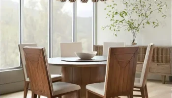 DS9 - Circular wood tabletop with angular wooden chairs under a modern chandelier beside a large window