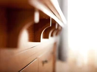Artistic perspective shot showing row of repeating wooden corbel brackets along bedroom furniture creating rhythmic shadow pattern in quartersawn oak