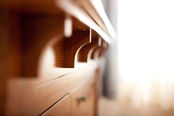Artistic perspective shot showing row of repeating wooden corbel brackets along bedroom furniture creating rhythmic shadow pattern in quartersawn oak
