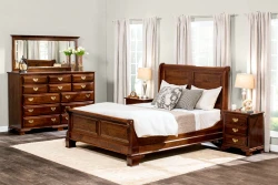Classic sleigh bedroom collection with queen bed tall chest and nightstands in mahogany finish featuring brass hardware white bedding and traditional styling
