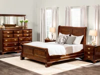 Classic sleigh bedroom collection with queen bed tall chest and nightstands in mahogany finish featuring brass hardware white bedding and traditional styling