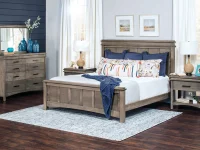 Coastal farmhouse bedroom collection in weathered gray featuring panel bed dresser and nightstands with navy accents blue glass vases and seascape artwork