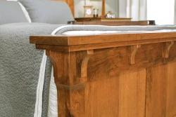 Craftsman style bed detail highlighting solid wood construction decorative corbels layered crown molding and traditional joinery in warm oak finish