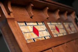 Detailed view of Artistic stained glass panels in headboard featuring geometric pattern with amber glass and red diamond accents framed in oak