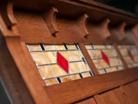 Detailed view of Artistic stained glass panels in headboard featuring geometric pattern with amber glass and red diamond accents framed in oak