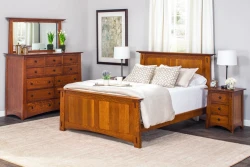 Mission style bedroom suite in quartersawn oak featuring panel bed tall dresser and nightstands with black hardware neutral bedding and botanical artwork