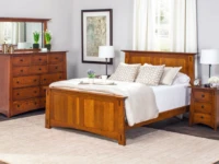 Mission style bedroom suite in quartersawn oak featuring panel bed tall dresser and nightstands with black hardware neutral bedding and botanical artwork