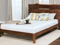 Modern Asian inspired platform bed in live edge walnut with floating base matching chest bright yellow bedding and geometric oriental artwork above