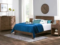 Modern farmhouse bedroom set with dark wood frame bed matching dresser and nightstands featuring navy quilted bedding and turquoise feather accent pillows