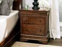 Nightstand in rich brown featuring two drawers with decorative pulls stepped crown molding and traditional bracket details styled with glass accessories