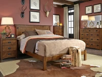Rustic craftsman bedroom set with planked headboard bed and coordinating case pieces in distressed oak featuring antler decor and botanical prints