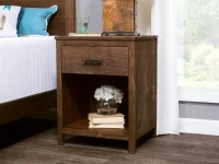 Rustic wooden nightstand with single drawer hardware pull featuring open shelf storage space decorated with white hydrangeas and stacked books