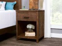 Rustic wooden nightstand with single drawer hardware pull featuring open shelf storage space decorated with white hydrangeas and stacked books