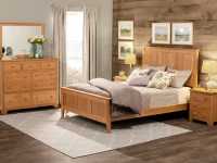 Shaker style bedroom set featuring solid oak panel bed dresser and nightstands with simple round pulls accented by landscape artwork and gray bedding