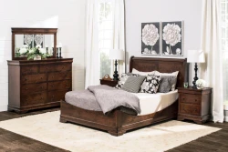 Traditional Louis Philippe bedroom set in dark cherry featuring sleigh bed dresser with mirror and nightstands accented by black lamps and botanical artwork