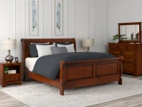 Traditional Louis Philippe sleigh bed set in warm cherry featuring curved panels dresser and nightstand with mercury glass lamps and blue feather artwork