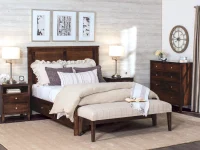 Traditional bedroom suite in rich brown featuring panel bed matching nightstands and chest with plaid bench monochromatic artwork and brushed nickel lamps