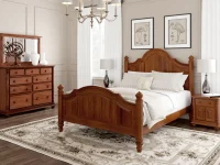 Traditional bedroom suite with arched poster bed matching dresser and nightstands in warm cherry featuring ornate turned posts and classic flamingo artwork
