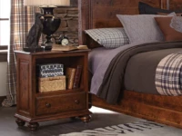 Traditional bun foot nightstand in distressed cherry featuring open shelf storage drawer turned legs styled with dog lamp plaid bedding and rustic decor