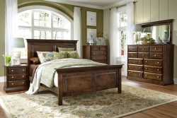 Traditional panel bed set in distressed walnut featuring crown molding dresser with mirror nightstands and chrome knobs styled with sage floral bedding