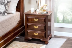 Traditional three-drawer nightstand in dark cherry wood featuring brass chippendale pulls decorative bracket feet and styled with silver vase fresh flowers