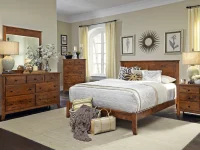 Traditional wood bedroom collection with panel bed dresser and nightstands in warm brown finish complemented by cream walls botanical prints and sunburst mirror