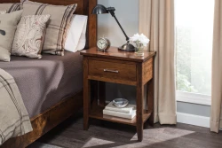 Transitional Shaker nightstand in brown maple featuring single drawer chrome pull open shelf tapered legs styled with industrial task lamp and white hydrangeas
