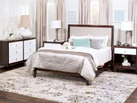 Transitional bedroom collection featuring dark wood frame upholstered panel bed white drawer dresser nightstand set with brushed nickel hardware and floral rug