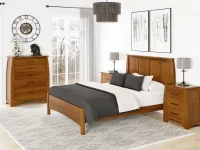 Transitional solid oak bedroom collection with panel bed chest and nightstands in honey finish featuring black hardware abstract art and oversized drum pendant