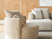 Rowe - Beige shaggy armchair with plush cushions, placed on a light rug alongside a beige sofa, with a floor lamp and framed artwork on a wooden paneled wall