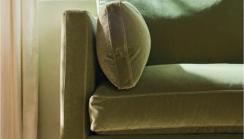 Rowe - Close-up view of a green velvet sofa with plush cushions, featuring visible stitching and wooden legs