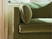 Rowe - Close-up view of a green velvet sofa with plush cushions, featuring visible stitching and wooden legs