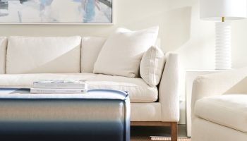 Rowe - Cream Sofa With Plush Cushions Near White Lamp And Ottoman Under Abstract Art Home Decor