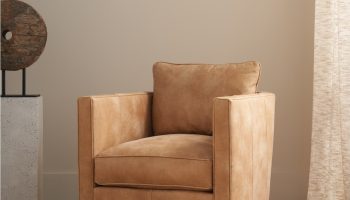 Rowe - Tan Swivel Armchair With Plush Cushions On Woven Rug Near Abstract Sculpture