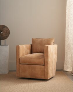 Rowe - Tan Swivel Armchair With Plush Cushions On Woven Rug Near Abstract Sculpture