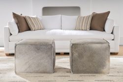 Rowe - Two Grey Cowhide Ottomans In Front Of White Sofa With Brown And Striped Pillows Home Decor