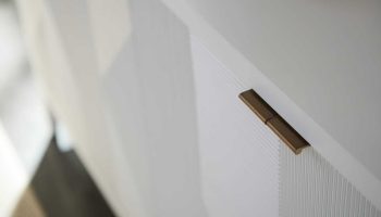 Rowe - White Cabinet With Brass Handle And Ribbed Panel Door In Modern Home Decor