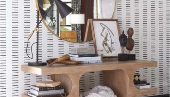 Rowe - Wooden Console Table With Books And Decor Under Large Round Mirror Near Striped Wallpaper
