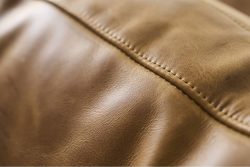 Rowe - close-up view of tan leather upholstery section featuring finely stitched seam running vertically
