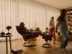 Dad relaxing in dark caramel Stressless Mayfair recliner while kids play