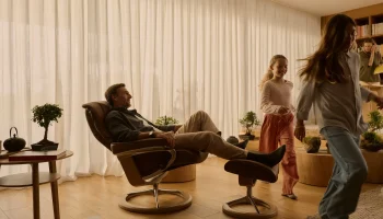 Dad relaxing in dark caramel Stressless Mayfair recliner while kids play
