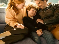 Happy family cuddling on grey Stressless Emily sofa