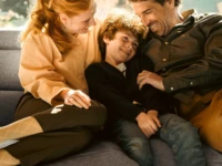 Happy family cuddling on grey Stressless Emily sofa