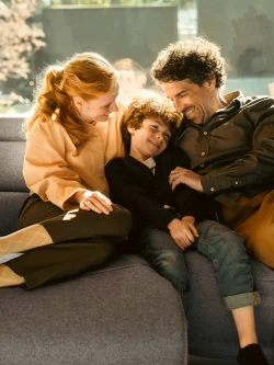 Happy family cuddling on grey Stressless Emily sofa