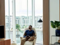 Man relaxing in vanilla walnut Stressless Max recliner by city window